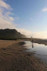 Man standing on beach against sky during sunset