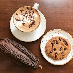 High angle view of cappuccino and cookie on table