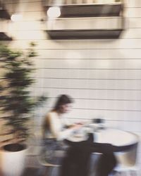 Side view of blurred motion of woman walking by wall