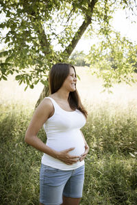 Side view of young woman standing on grassy field