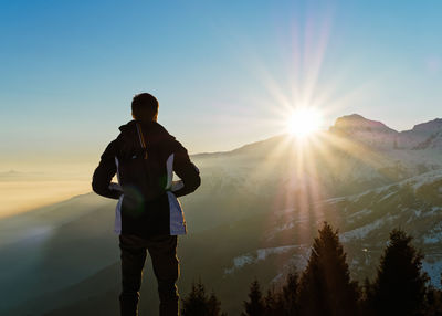 Rear view of silhouette man standing on mountain against sky