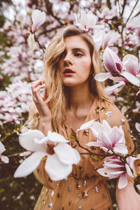 Close-up of woman with pink flowers against tree