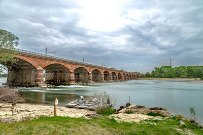 Arch bridge over river against sky