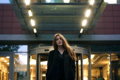 Portrait of young woman standing in illuminated building