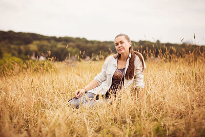 Portrait of a confident authentic woman sitting in a field in the countryside
