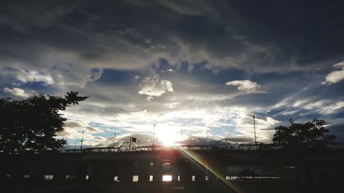 Silhouette bridge and buildings against sky during sunset