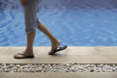 Low section of woman walking at poolside