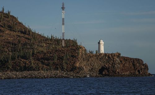 Lighthouse by sea against sky