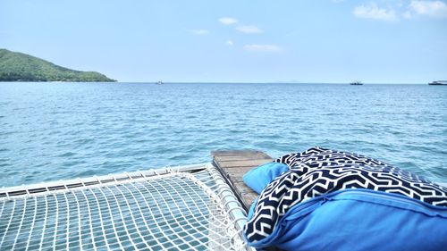 Low section of shoes by swimming pool against sky