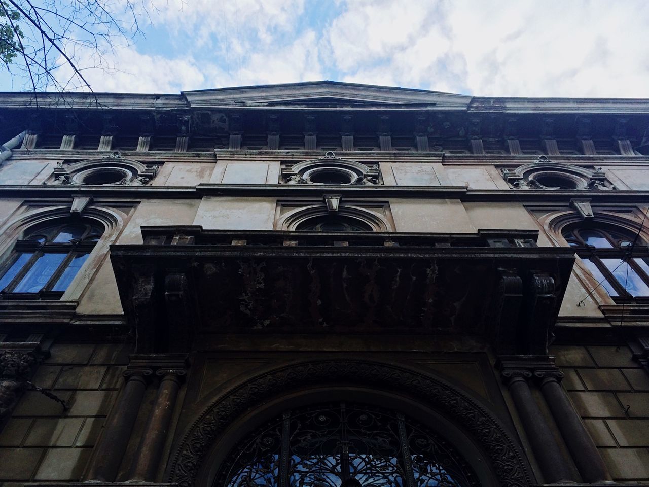 architecture, low angle view, built structure, building exterior, sky, arch, human representation, window, building, art and craft, day, art, cloud - sky, statue, sculpture, city, outdoors, cloud, creativity