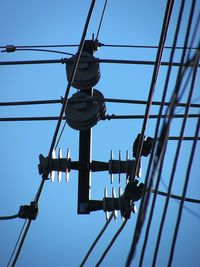 Low angle view of electricity pylon against clear blue sky