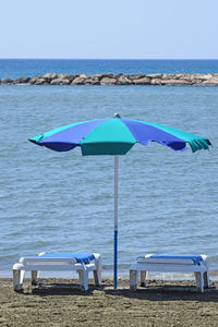 Deck chairs on beach against sky