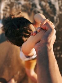 Pov perspective of the hand of a father holding tight to the hands of his child at the shore