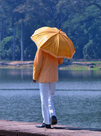 Rear view of men with umbrella standing in lake