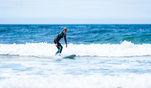 Full length of woman surfing in sea against clear sky