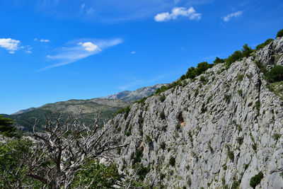 Low angle view of rocky mountains against blue sky