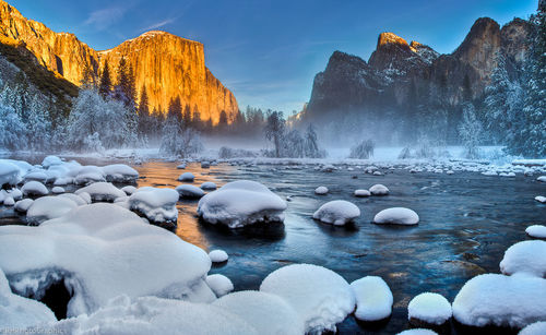 Calm lake against rocky mountain range during winter