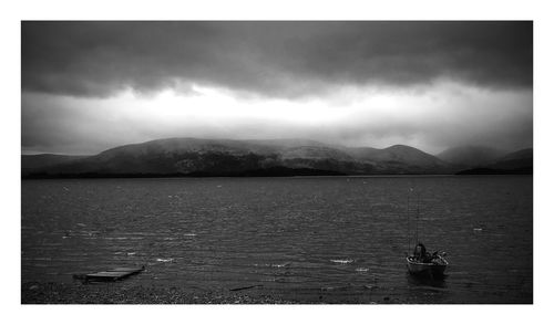 Scenic view of lake and mountains against storm clouds