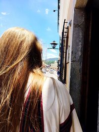 Rear view of woman standing against sky in city