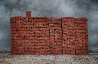 View of red bricks stacked against grey concrete wall