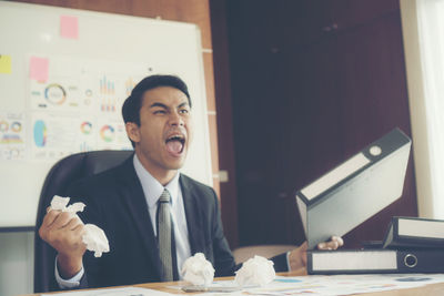 Angry businessman throwing paper balls in office