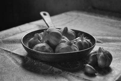 Close-up of garlic bulbs in saucepan on table at home