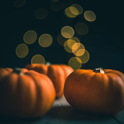 Three little pumpkins on a dark background with yellow bokeh light