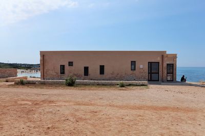 Exterior of old building by beach against sky