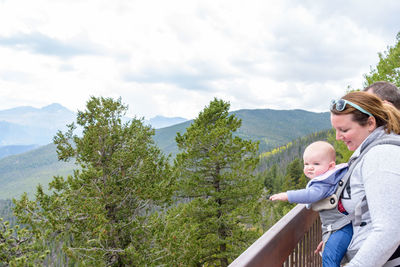 Mother and daughter by railing against sky