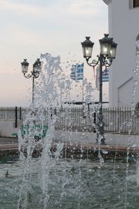 Fountain in city against sky