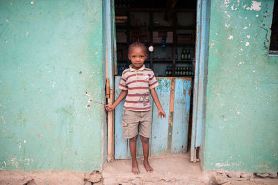 Portrait of happy boy standing against door