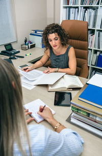 Young woman using mobile phone while sitting on table