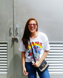 Portrait of smiling young woman standing against closed door