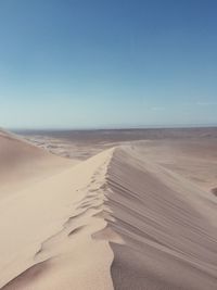 Sand dunes at beach against clear sky