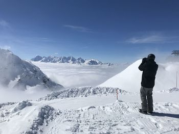 Man standing on snowcapped mountain against sky