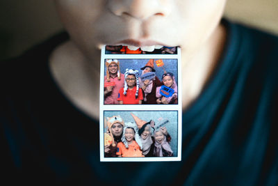 Midsection of boy holding photographs in mouth