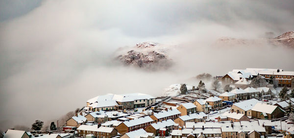 Panoramic view of snow covered houses and buildings against sky