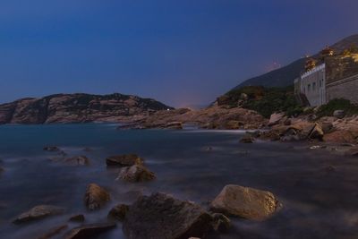 Scenic view of sea and mountains against clear blue sky