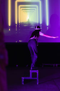 Businesswoman looking at projection screen while standing on ladder in exhibition center