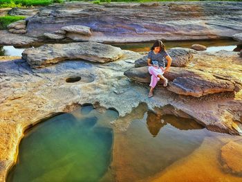 High angle view of woman sitting on rock at beach