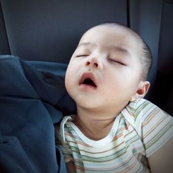 Close-up of cute baby boy sleeping in car