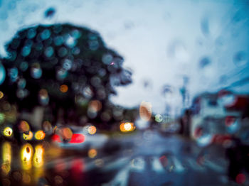 Illuminated city street seen through wet car windshield