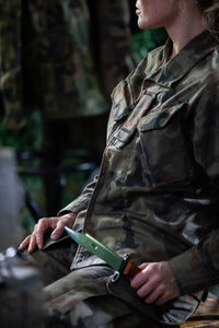 A military lady in a moro uniform sits on a chair with a bayonet in her hand. 