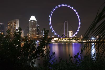 Illuminated city by river at night