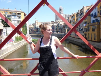 Woman standing on bridge against river in city