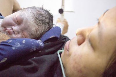 Newborn baby lying on woman