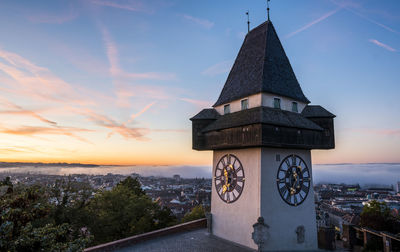 Clock tower amidst buildings against sky during sunset