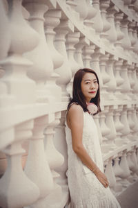 Portrait of young woman standing against wall