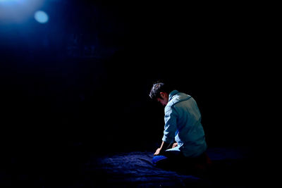 Man sitting on stage against black background