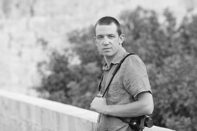 Portrait of young man standing against railing